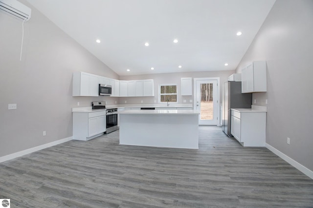 5203 NE Myers Rd, Kalkaska, MI 49646 - kitchen with stainless steel appliances, a kitchen island, a wall mounted air conditioner, recessed lighting, and white cabinets