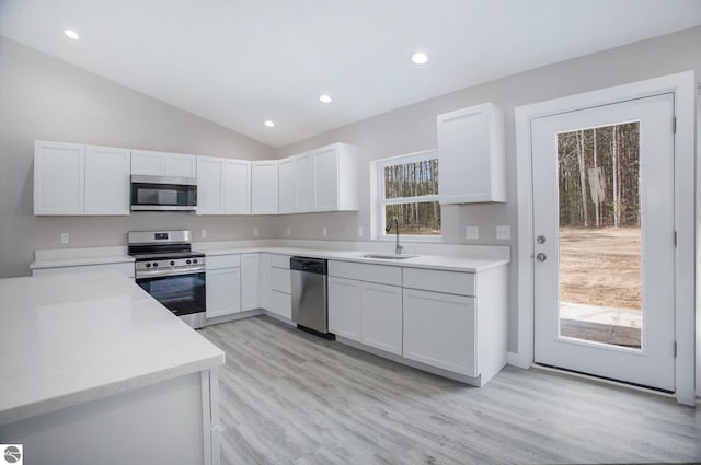 5203 NE Myers Rd, Kalkaska, MI 49646 - kitchen with stainless steel appliances, a sink, white cabinets, lofted ceiling, and light wood-type flooring