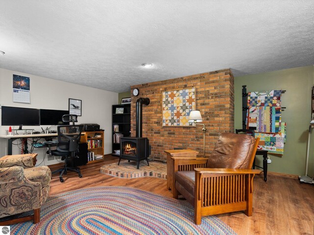 6307 Summit Ct, Traverse City, MI 49686 - living room with wood finished floors, a textured ceiling, a wood stove, an office area, and baseboards