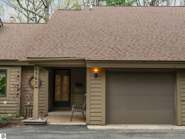 6307 Summit Ct, Traverse City, MI 49686 - view of exterior entry featuring roof with shingles and an attached garage