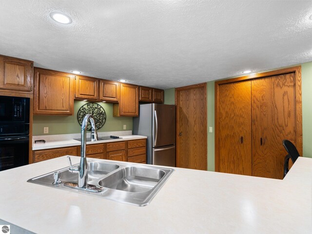 6307 Summit Ct, Traverse City, MI 49686 - kitchen with black appliances, a sink, light countertops, brown cabinets, and a textured ceiling