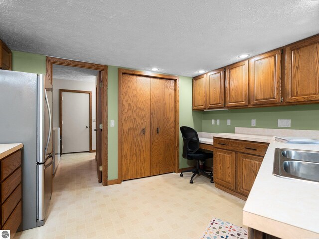 6307 Summit Ct, Traverse City, MI 49686 - kitchen featuring freestanding refrigerator, light countertops, brown cabinets, a textured ceiling, and recessed lighting