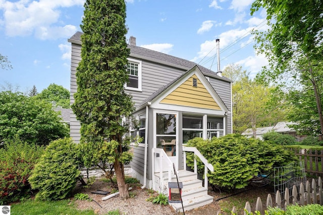 618 E Illinois St, Mount Pleasant, MI 48858 - view of front of home featuring fence, a sunroom, a chimney, and roof with shingles