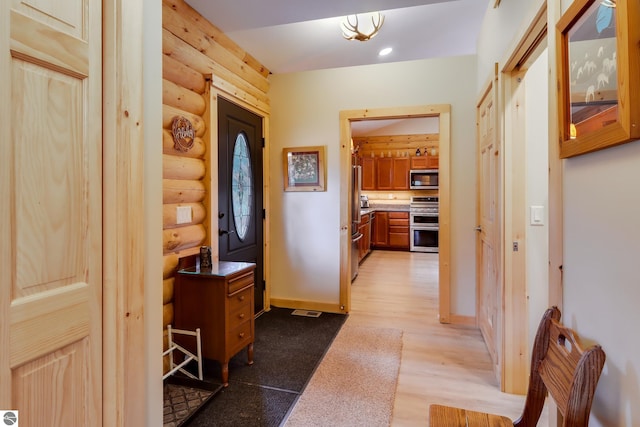 entryway with log walls, wood finished floors, and baseboards