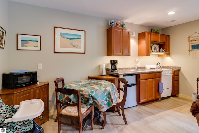 kitchen with white gas range, fridge, light wood-style flooring, brown cabinetry, and recessed lighting