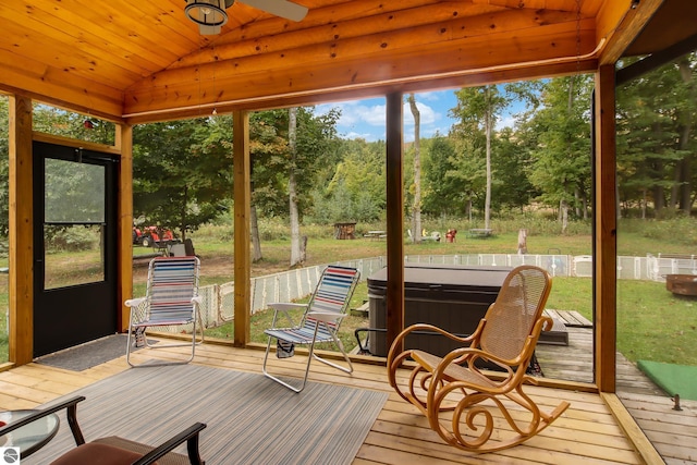 sunroom with lofted ceiling, view of scattered trees, and ceiling fan