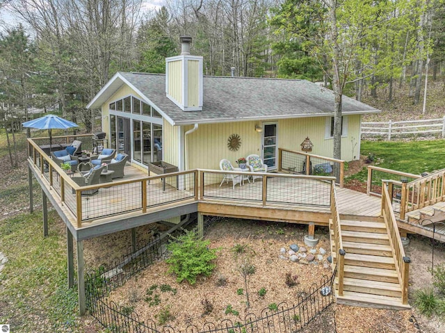224 Island View Dr, Traverse City, MI 49696 - rear view of house featuring roof with shingles, fence, a deck, a chimney, and an outdoor hangout area
