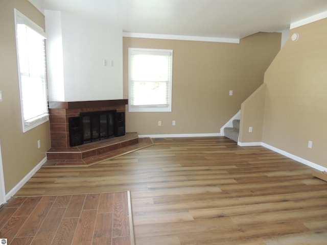 1117 Lincoln Dr, Lake Isabella, MI 48893 - unfurnished living room featuring stairs, baseboards, wood finished floors, and a glass covered fireplace