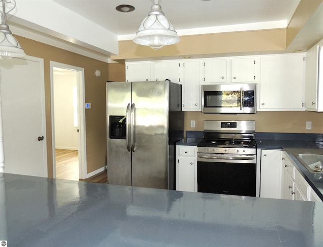 1117 Lincoln Dr, Lake Isabella, MI 48893 - kitchen featuring appliances with stainless steel finishes, dark countertops, white cabinets, and decorative light fixtures