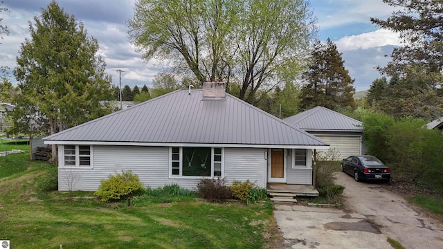 660 N Michigan Ave, Manton, MI 49663 - view of front of house featuring metal roof, a front lawn, a chimney, and a garage