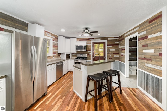 11749 Birch Dr, Lakeview, MI 48850 - kitchen featuring stainless steel appliances, wooden walls, a ceiling fan, dark countertops, and white cabinets