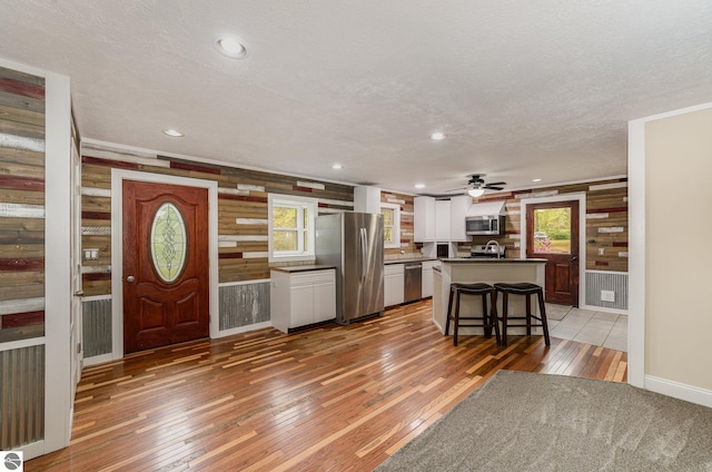 11749 Birch Dr, Lakeview, MI 48850 - kitchen with appliances with stainless steel finishes, light wood finished floors, healthy amount of natural light, a textured ceiling, and dark countertops