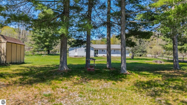 11401 Orchard Dr, Rapid City, MI 48622 - view of green lawn featuring a shed, an outdoor structure, and view of wooded area