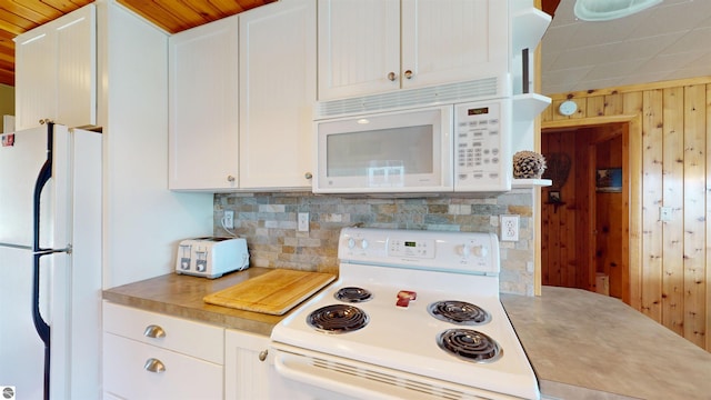 10701 SW Torch Lake Dr, Rapid City, MI 49676 - kitchen featuring white appliances, wooden walls, white cabinetry, light countertops, and decorative backsplash