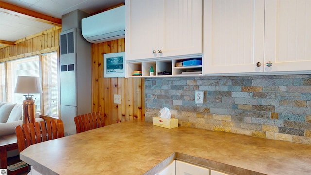 10701 SW Torch Lake Dr, Rapid City, MI 49676 - kitchen with a wall unit AC, beam ceiling, white cabinetry, wooden walls, and light countertops