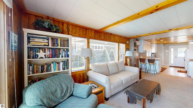 10701 SW Torch Lake Dr, Rapid City, MI 49676 - living room featuring wooden walls, healthy amount of natural light, light carpet, and beamed ceiling