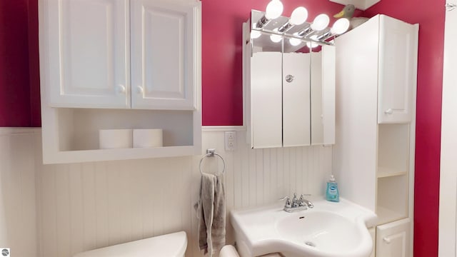 10701 SW Torch Lake Dr, Rapid City, MI 49676 - half bath featuring toilet, a sink, and a wainscoted wall