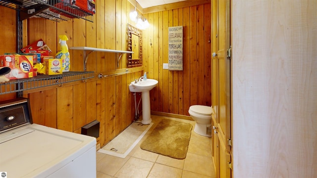 10701 SW Torch Lake Dr, Rapid City, MI 49676 - bathroom featuring washer / dryer, wooden walls, toilet, a sink, and tile patterned flooring