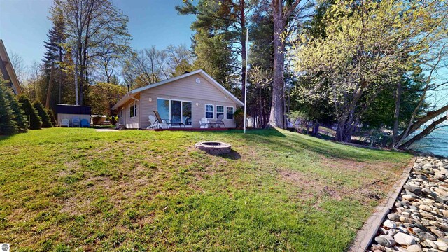 10701 SW Torch Lake Dr, Rapid City, MI 49676 - back of property featuring a fire pit and a yard