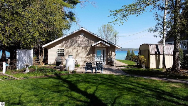 10701 SW Torch Lake Dr, Rapid City, MI 49676 - rear view of house with a storage unit, a yard, an outbuilding, and a patio area