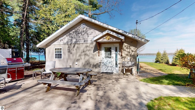 10701 SW Torch Lake Dr, Rapid City, MI 49676 - view of front of house with a patio area, a water view, outdoor dining space, and a front yard