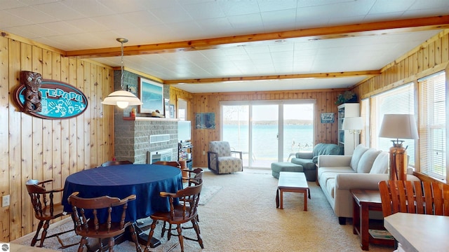 10701 SW Torch Lake Dr, Rapid City, MI 49676 - living room featuring wooden walls, light carpet, a water view, and a glass covered fireplace