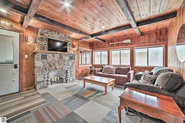 carpeted living room featuring wood ceiling, wooden walls, beamed ceiling, and a fireplace