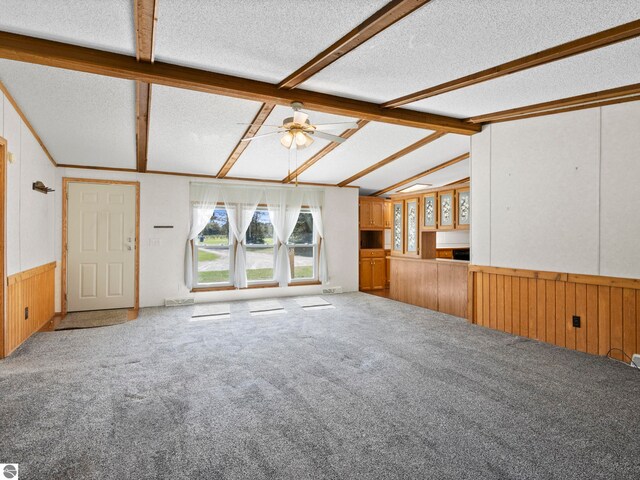 5891 N 19th Rd, Mesick, MI 49668 - unfurnished living room featuring a textured ceiling, plenty of natural light, carpet, a wainscoted wall, and wood walls