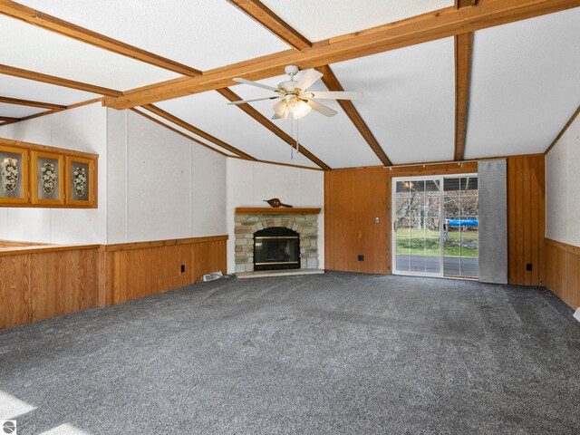 5891 N 19th Rd, Mesick, MI 49668 - unfurnished living room with carpet floors, wooden walls, ceiling fan, a stone fireplace, and a wainscoted wall
