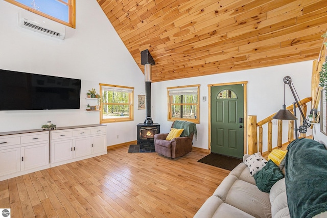 9266 Kenyon Trl, Frederic, MI 49733 - living area featuring a wood stove, an AC wall unit, high vaulted ceiling, baseboards, and light wood-style floors