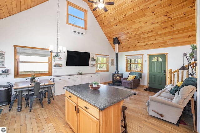 9266 Kenyon Trl, Frederic, MI 49733 - living area with a wall mounted AC, high vaulted ceiling, a wood stove, a ceiling fan, and light wood-style floors