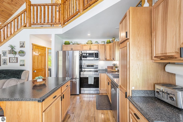 9266 Kenyon Trl, Frederic, MI 49733 - kitchen featuring appliances with stainless steel finishes, dark countertops, light wood-type flooring, a center island, and a towering ceiling