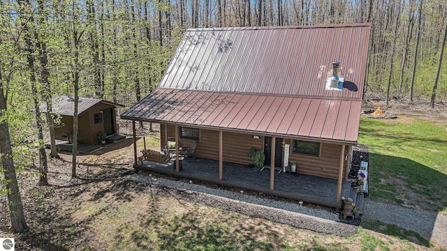9266 Kenyon Trl, Frederic, MI 49733 - view of front of home featuring faux log siding, metal roof, a view of trees, and an outbuilding