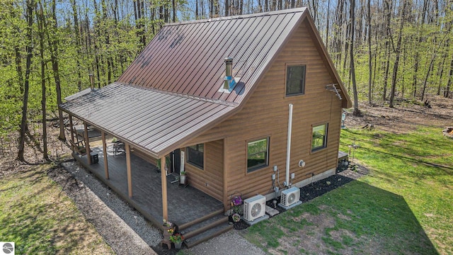 9266 Kenyon Trl, Frederic, MI 49733 - rear view of house with ac unit, metal roof, a yard, and a forest view