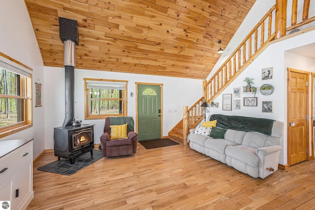 9266 Kenyon Trl, Frederic, MI 49733 - living area featuring a wood stove, stairs, light wood-style floors, healthy amount of natural light, and high vaulted ceiling