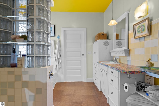 203 W 2nd St, Elk Rapids, MI 49629 - kitchen featuring a sink, decorative backsplash, hanging light fixtures, and white cabinetry