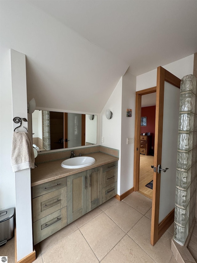 bathroom featuring vanity, tile patterned floors, lofted ceiling, and baseboards