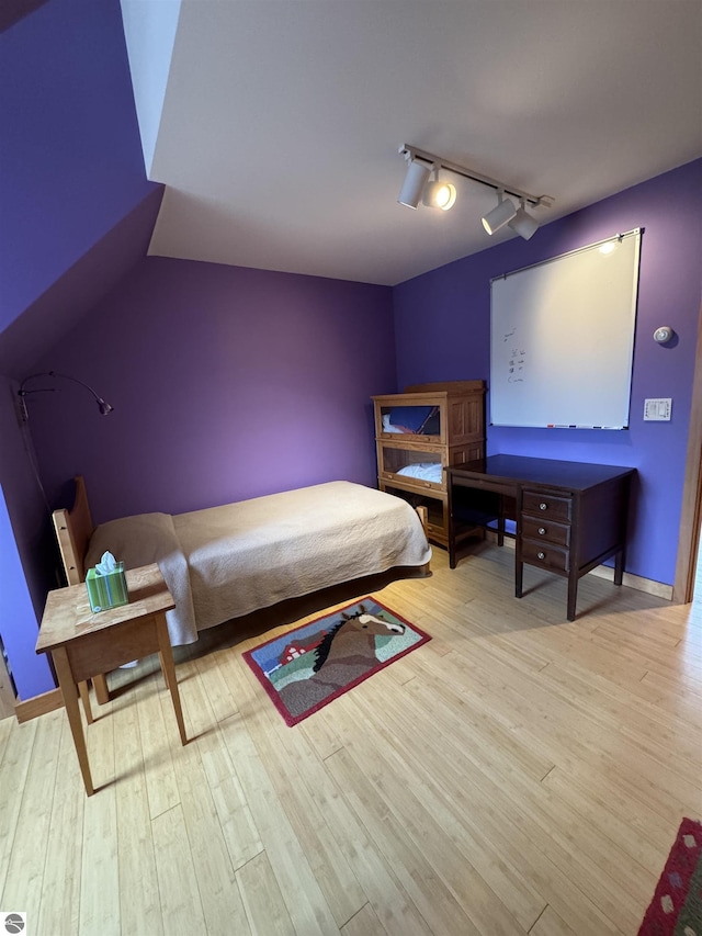 bedroom with rail lighting and light wood-style flooring
