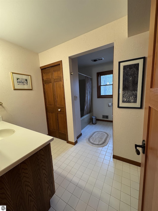 bathroom featuring tile patterned floors, shower / tub combo, vanity, and baseboards
