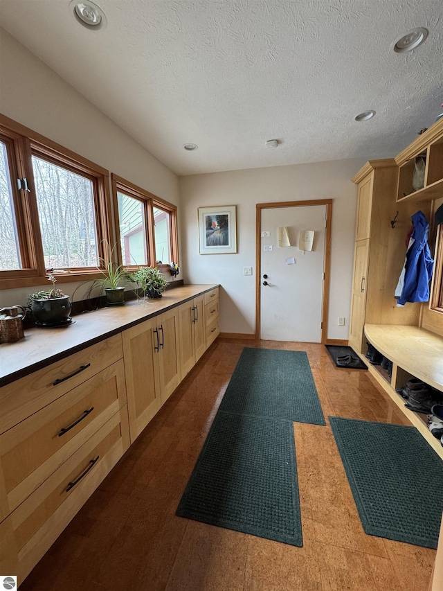 mudroom featuring a textured ceiling, recessed lighting, and baseboards