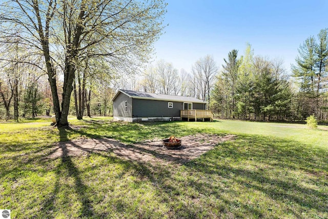 3218 S 41st Rd, Cadillac, MI 49601 - view of green lawn featuring a fire pit and a wooden deck
