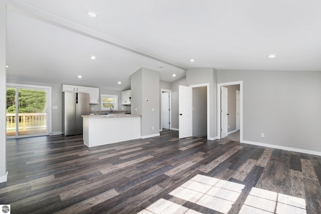 3218 S 41st Rd, Cadillac, MI 49601 - unfurnished living room with vaulted ceiling, plenty of natural light, dark wood-style flooring, baseboards, and recessed lighting