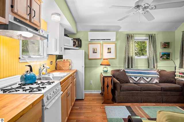 429 S Shabwasung St, Northport, MI 49670 - kitchen featuring white appliances, an AC wall unit, under cabinet range hood, a sink, and dark wood-style floors