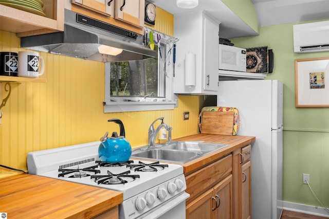 429 S Shabwasung St, Northport, MI 49670 - kitchen with white appliances, butcher block countertops, under cabinet range hood, a sink, and a wall mounted air conditioner