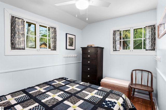 429 S Shabwasung St, Northport, MI 49670 - bedroom with wood finished floors, vaulted ceiling, a ceiling fan, and wainscoting