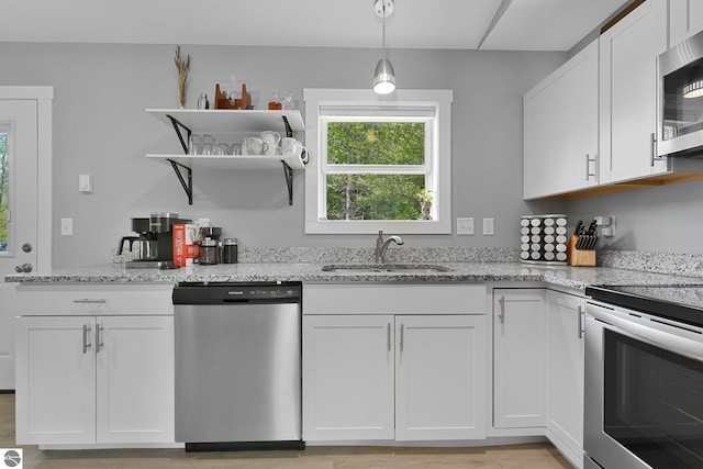 kitchen with appliances with stainless steel finishes, a sink, white cabinets, light stone countertops, and open shelves