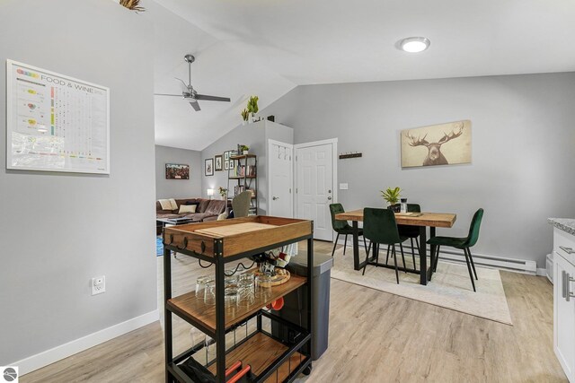 dining space featuring lofted ceiling, a ceiling fan, light wood-style floors, and baseboards