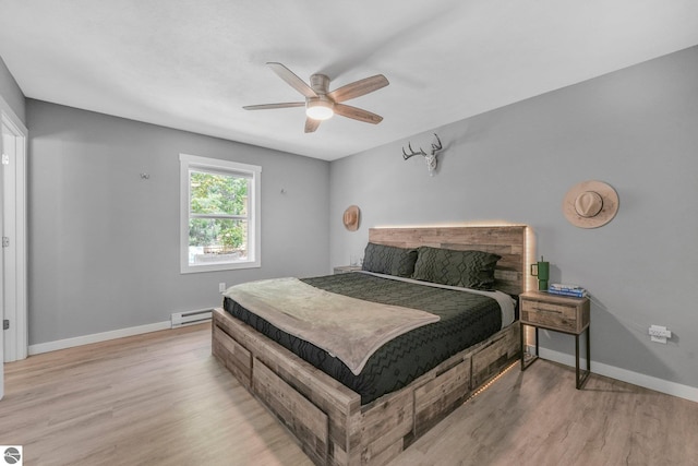bedroom with a baseboard heating unit, wood finished floors, baseboards, and ceiling fan