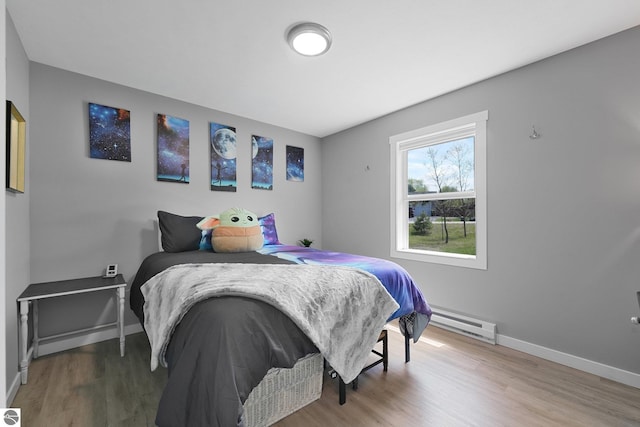 bedroom featuring baseboard heating, wood finished floors, and baseboards