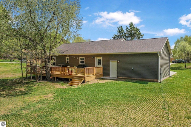rear view of property with a deck, a lawn, and a shingled roof